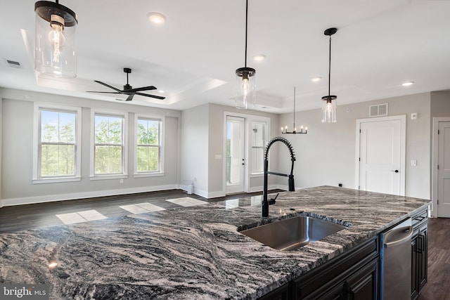 kitchen featuring a sink, a ceiling fan, baseboards, dark wood-type flooring, and a tray ceiling