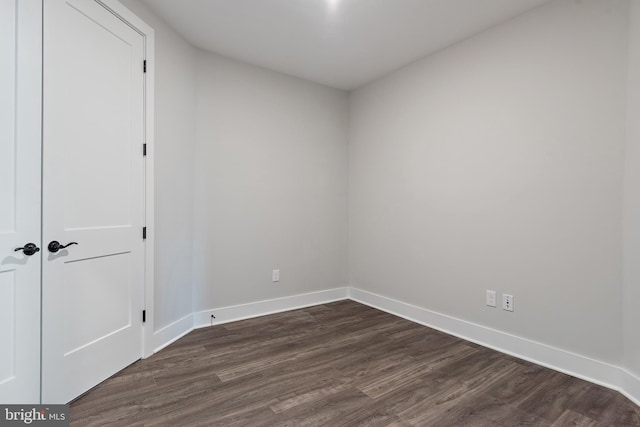 unfurnished room with baseboards and dark wood-type flooring