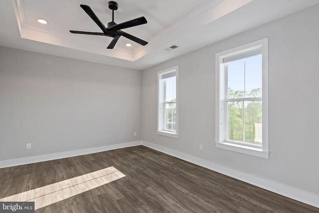 unfurnished room with recessed lighting, baseboards, dark wood-type flooring, a tray ceiling, and visible vents