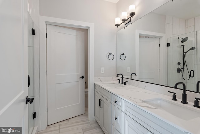 full bathroom with double vanity, a sink, a stall shower, and toilet