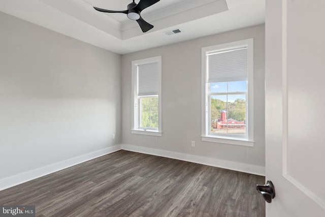 empty room with a tray ceiling, baseboards, dark wood-type flooring, and visible vents