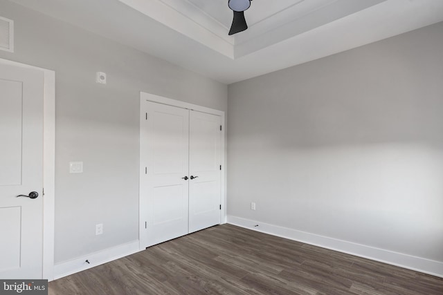 unfurnished bedroom with baseboards, a ceiling fan, a closet, and dark wood finished floors
