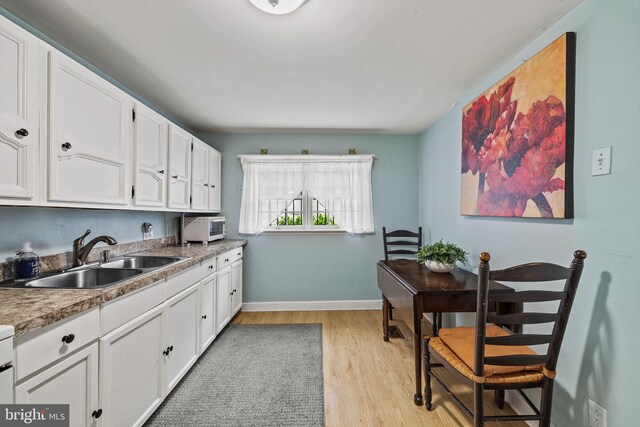 248 Greenwich St, Philadelphia, PA 19147 - kitchen with white cabinets, light wood-type flooring, baseboards, and a sink