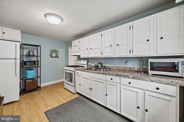 248 Greenwich St, Philadelphia, PA 19147 - kitchen with white cabinets, under cabinet range hood, a sink, and white appliances