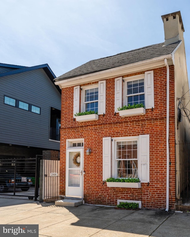 248 Greenwich St, Philadelphia, PA 19147 - view of front of property with brick siding, roof with shingles, a chimney, and fence