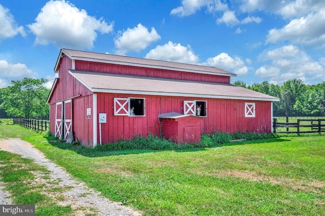 view of barn with fence and a yard