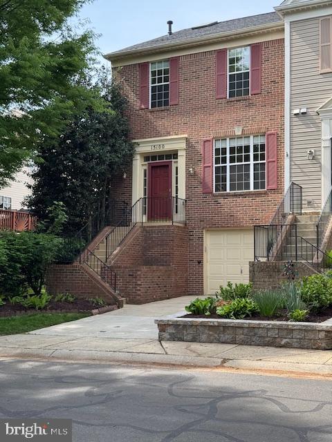townhome / multi-family property with driveway, a garage, and brick siding