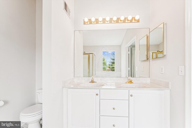 bathroom with visible vents, toilet, double vanity, and a sink