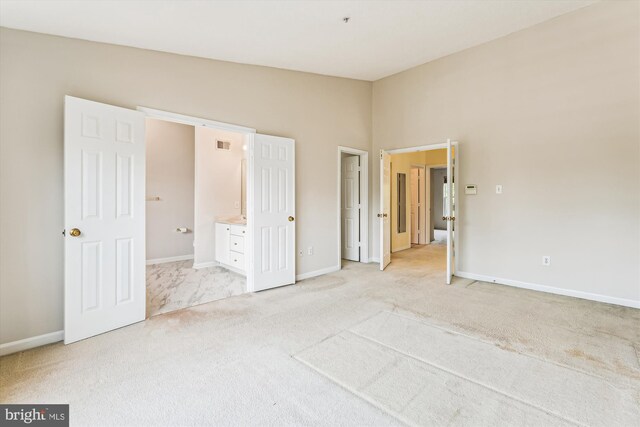 unfurnished bedroom featuring baseboards, visible vents, connected bathroom, and carpet