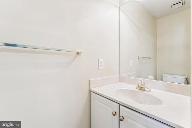 bathroom featuring toilet, visible vents, and vanity