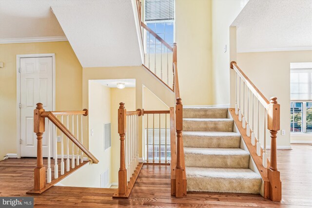 staircase featuring ornamental molding, visible vents, wood finished floors, and baseboards