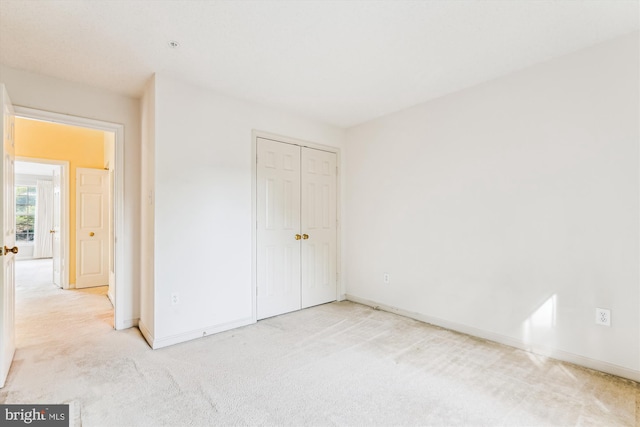 unfurnished bedroom featuring baseboards, a closet, and light colored carpet