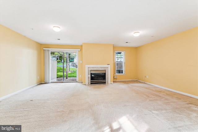 unfurnished living room featuring a premium fireplace, a wealth of natural light, and baseboards