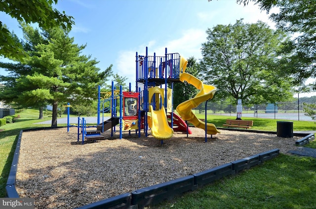 communal playground featuring fence and a lawn