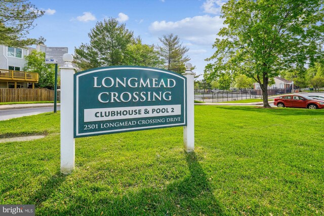 community sign with fence and a yard
