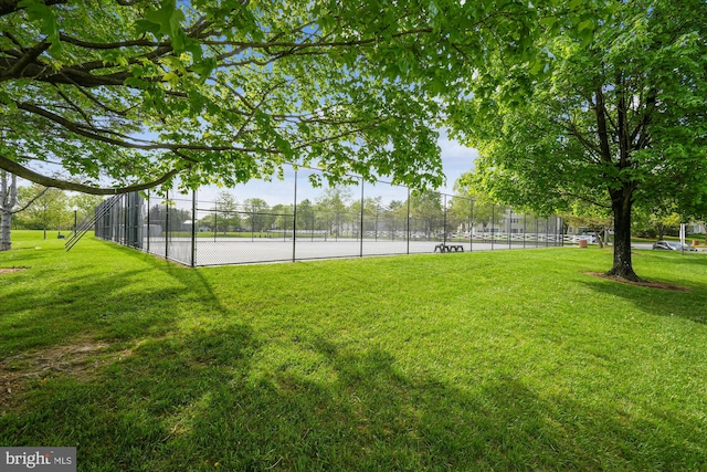 view of yard with a tennis court and fence