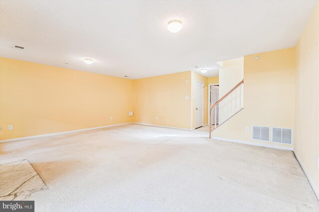 unfurnished room featuring stairway, visible vents, baseboards, and light carpet