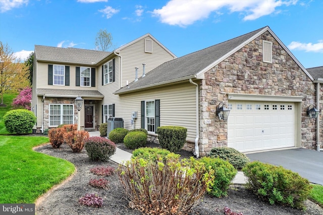 view of front facade with an attached garage, central AC, aphalt driveway, stone siding, and a front yard
