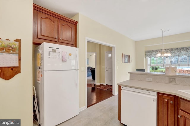 kitchen with light countertops, brown cabinetry, white appliances, and a chandelier