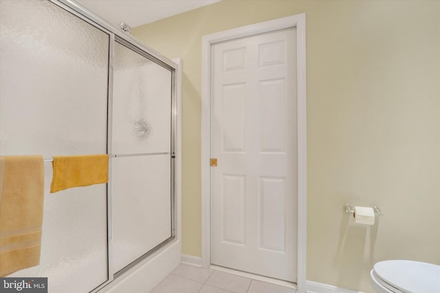 bathroom with toilet, tile patterned floors, a shower stall, and baseboards