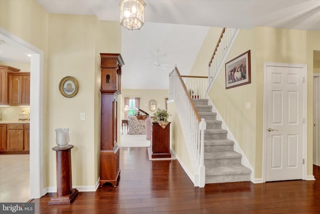 entrance foyer with baseboards, a high ceiling, stairway, hardwood / wood-style flooring, and ceiling fan with notable chandelier