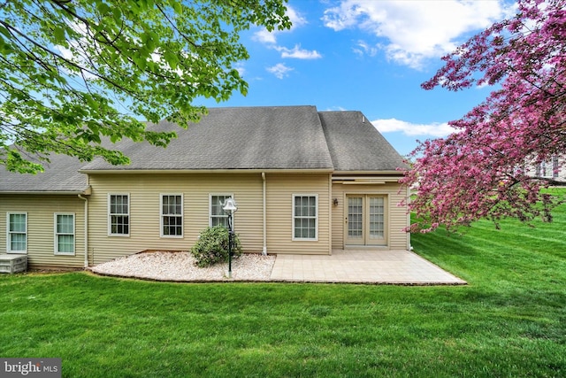 rear view of house featuring a lawn, roof with shingles, and a patio