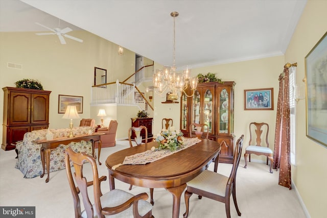 dining area featuring visible vents, crown molding, light colored carpet, stairway, and ceiling fan with notable chandelier