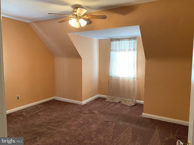 bonus room featuring ceiling fan, dark carpet, lofted ceiling, and baseboards