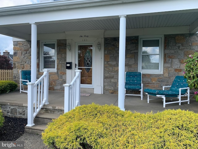 property entrance featuring stone siding and covered porch