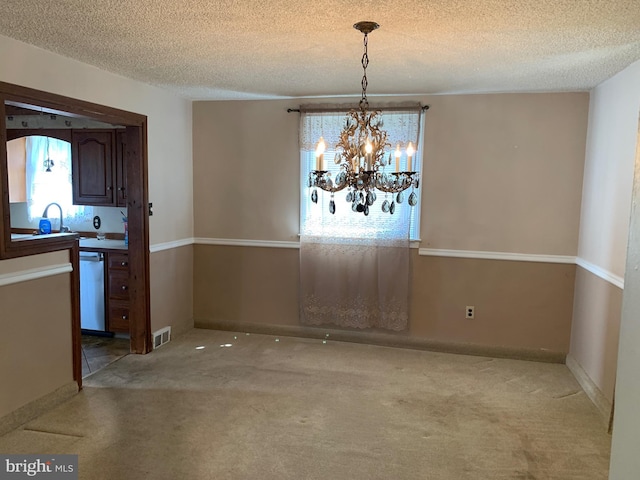 unfurnished dining area with carpet floors, a chandelier, and a textured ceiling