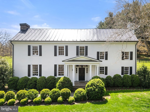 view of front of home featuring metal roof, a standing seam roof, stucco siding, and a chimney