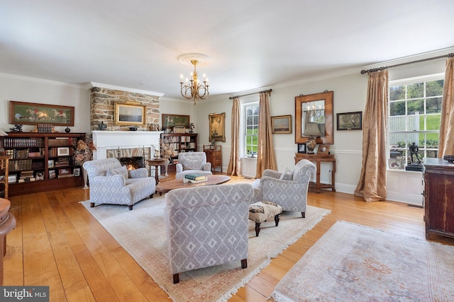 living area with crown molding, a notable chandelier, a large fireplace, and hardwood / wood-style floors