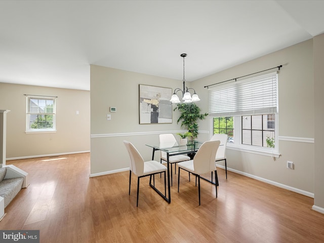 dining space featuring light wood-style floors, baseboards, and an inviting chandelier