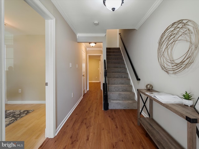 staircase featuring baseboards, ornamental molding, and wood finished floors