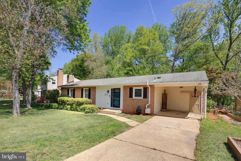 view of front of property with concrete driveway, a front lawn, a chimney, an attached carport, and brick siding