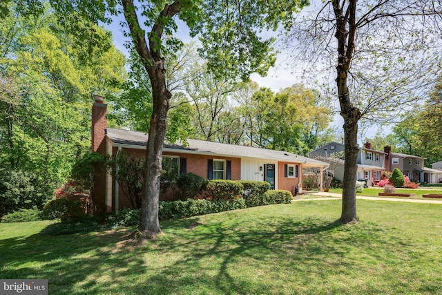 view of front of property with a chimney, brick siding, and a front yard