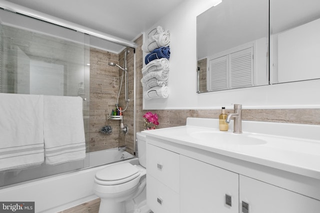 1301 20th St NW Unit 415, Washington, DC 20036 - bathroom featuring vanity, toilet, combined bath / shower with glass door, and tile walls