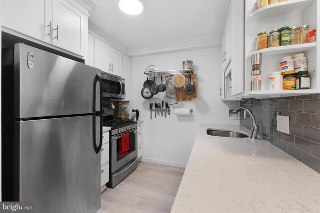 1301 20th St NW Unit 415, Washington, DC 20036 - kitchen featuring stainless steel appliances, backsplash, white cabinets, a sink, and light stone counters