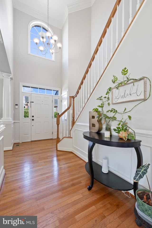 14401 Broadwinged Dr, Gainesville, VA 20155 - entryway with crown molding, light wood-type flooring, stairway, decorative columns, and a chandelier