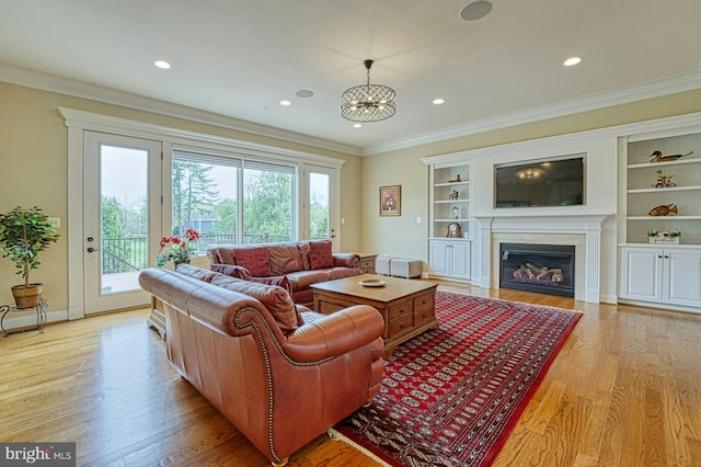 living area featuring baseboards, a glass covered fireplace, recessed lighting, light wood-style floors, and crown molding