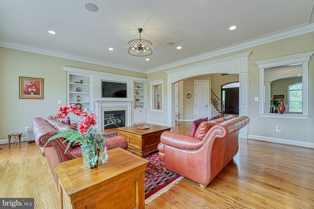 living room with light wood-style flooring, arched walkways, baseboards, crown molding, and a fireplace