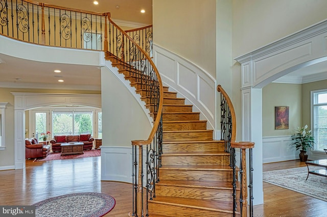stairway featuring arched walkways, ornamental molding, and a decorative wall
