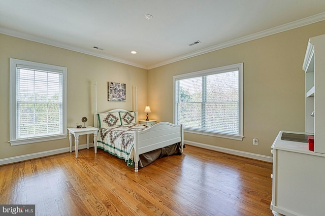 bedroom with light wood-style floors, visible vents, and crown molding