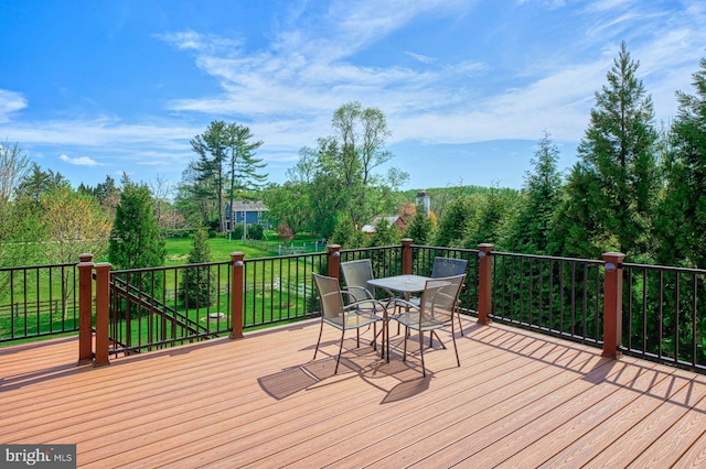 wooden deck featuring outdoor dining area and a lawn