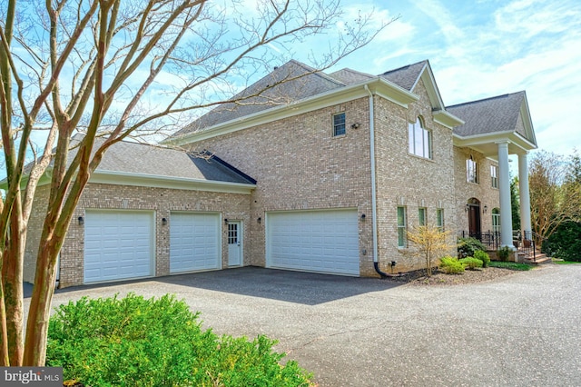 view of property exterior featuring brick siding, driveway, a shingled roof, and a garage