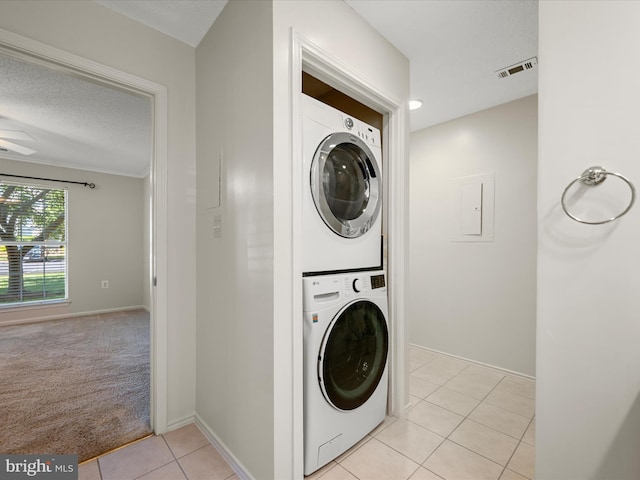 21019 Timber Ridge Ter Unit 102, Ashburn, VA 20147 - clothes washing area featuring stacked washer / dryer, light tile patterned floors, baseboards, a textured ceiling, and light colored carpet
