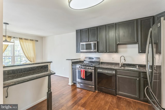 46878 Graham Cv, Sterling, VA 20165 - kitchen with baseboards, dark wood-style flooring, a sink, dark stone counters, and appliances with stainless steel finishes