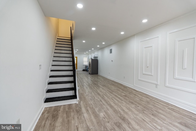 stairway featuring wood finished floors, baseboards, and recessed lighting
