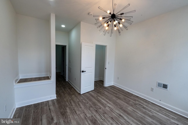 spare room featuring a chandelier, wood finished floors, baseboards, and recessed lighting