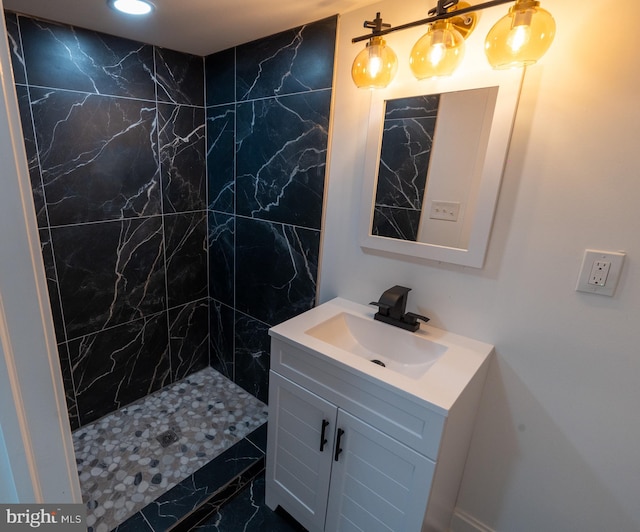 full bathroom featuring marble look tiles, vanity, and a tile shower